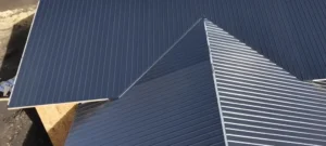 A clean dark blue corrugated metal residential roof with sharp peaks after its roof is cleaned.