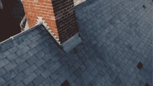 A clean dark gray slate roof with a red brick chimney after roof cleaning in Wilmington, NC.
