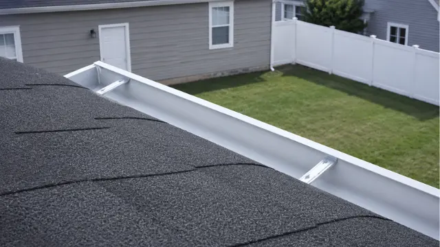 Clear white gutter on a shingle roof overlooking a fenced backyard - Gutter Cleaning in Wilmington, NC