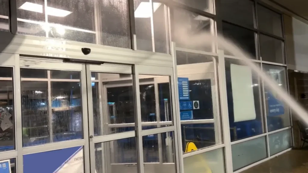 A glass front of a commercial storefront, being pressure washed.