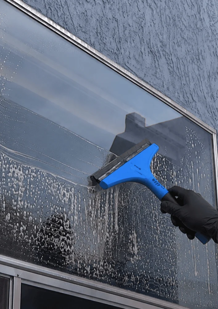 Commercial Window Squeegee Cleaning - Window Cleaning Wilmington, NC Technician using a blue squeegee on a large commercial window