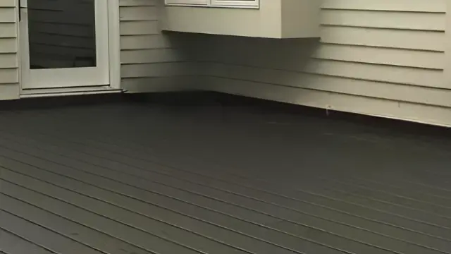 Dark gray deck beside light home siding