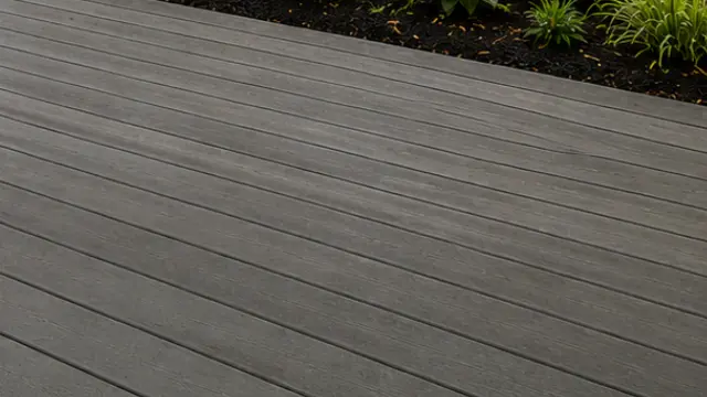 Close view of clean gray composite deck boards next to a garden bed