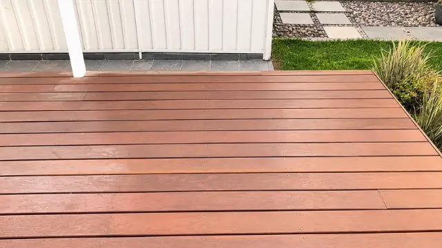 Clean red composite deck boards beside a white home and garden