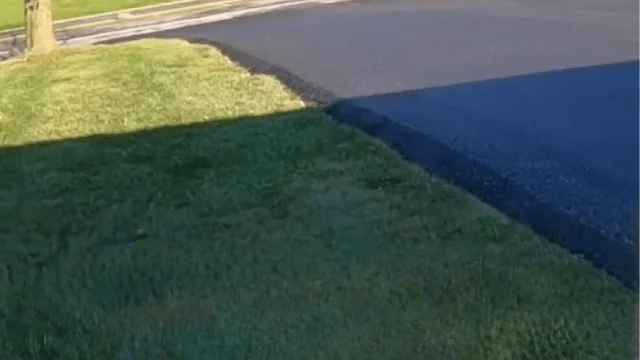 Fresh dark asphalt driveway beside a neat green lawn edge - Sidewalk Cleaning Wilmington, NC