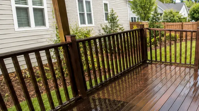 Freshly cleaned dark wood deck with railing overlooking a fenced backyard
