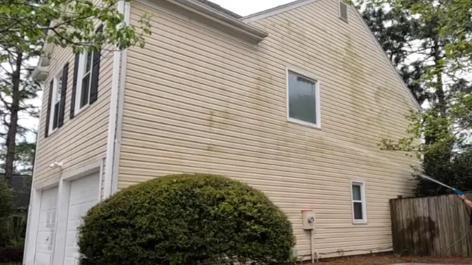 Washing mildew off beige vinyl siding on a two-story home, residential pressure washing in Wilmington NC