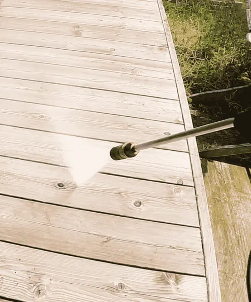 Pressure washer wand cleaning weathered gray deck boards