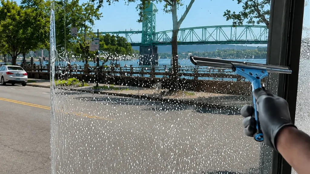 Window Cleaning Squeegee Cape Fear Bridge View - Window Cleaning Wilmington, NC Squeegee cleaning a storefront window with the Cape Fear bridge in view